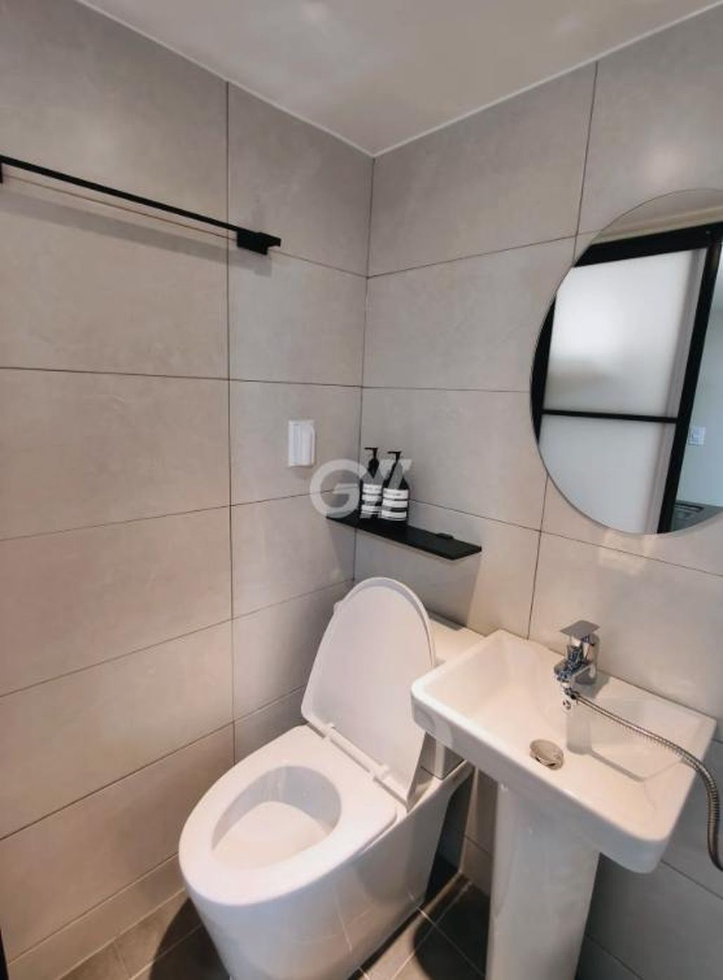 A modern bathroom with a toilet, sink, and a mirror.