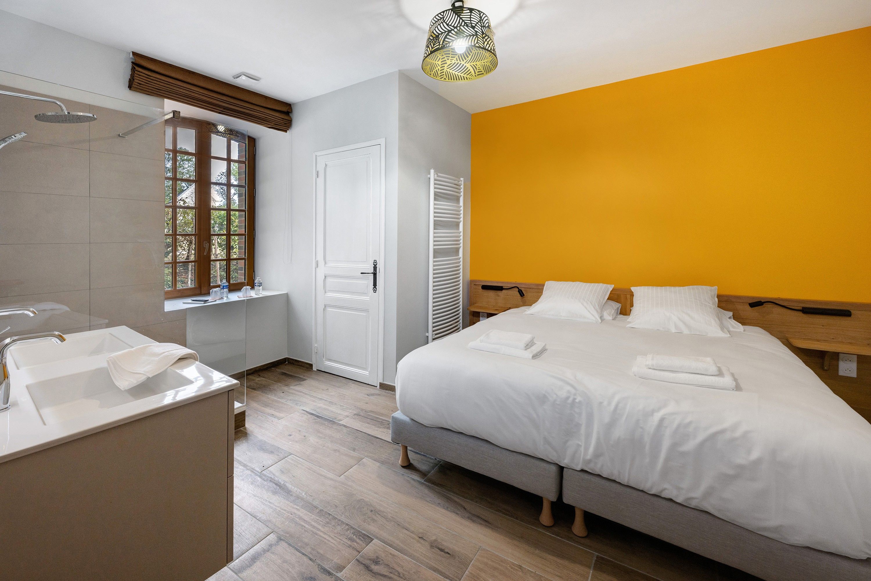 Ein Hotelzimmer mit einem Bett, einem Badezimmer mit Dusche, einem Fenster und einem Nachttisch.