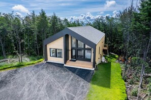 A modern house with a sloped roof, large windows, and a deck.