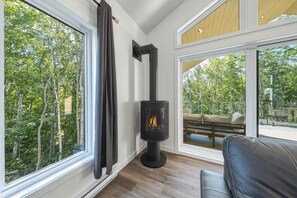 A room with a fireplace, large windows, and a view of the outdoors.