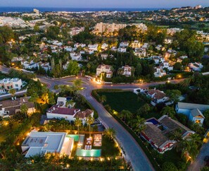 Eine Luftaufnahme eines Wohngebiets mit Häusern, Straßen und einem größeren Gebäude in der Ferne.
