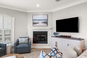 A living room with a fireplace, a television mounted on the wall, and a comfortable seating area. - 3BR Seagrove Beach Pet-Friendly Penthouse | Private Beach & Pool (Santa Rosa Beach)