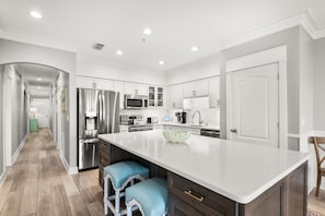 A modern kitchen with white cabinetry, stainless steel appliances, and a large island with stools. - 3BR Seagrove Beach Pet-Friendly Penthouse | Private Beach & Pool (Santa Rosa Beach)