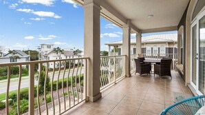 A balcony with a view of the street and neighboring houses, a table with chairs, and a blue chair. - 3BR Seagrove Beach Pet-Friendly Penthouse | Private Beach & Pool (Santa Rosa Beach)