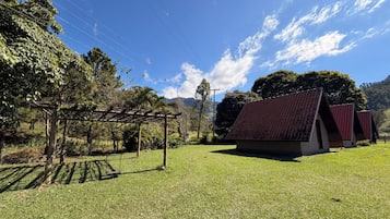 Ein Rasen mit einer hölzernen Pergola und einem kleinen Gebäude mit rotem Dach.