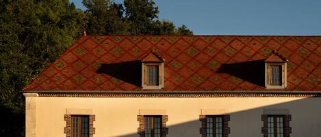 A building with a symmetrical facade, multiple windows, and a patterned roof.