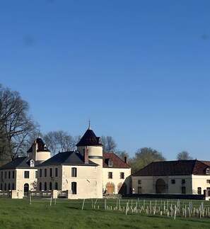 Ein großes Gebäude mit einem markanten Turm und Rundbogenfenstern, umgeben von einer gepflegten Rasenfläche.