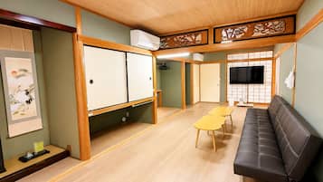 A room with a sofa, a table, a TV, and a sliding door.