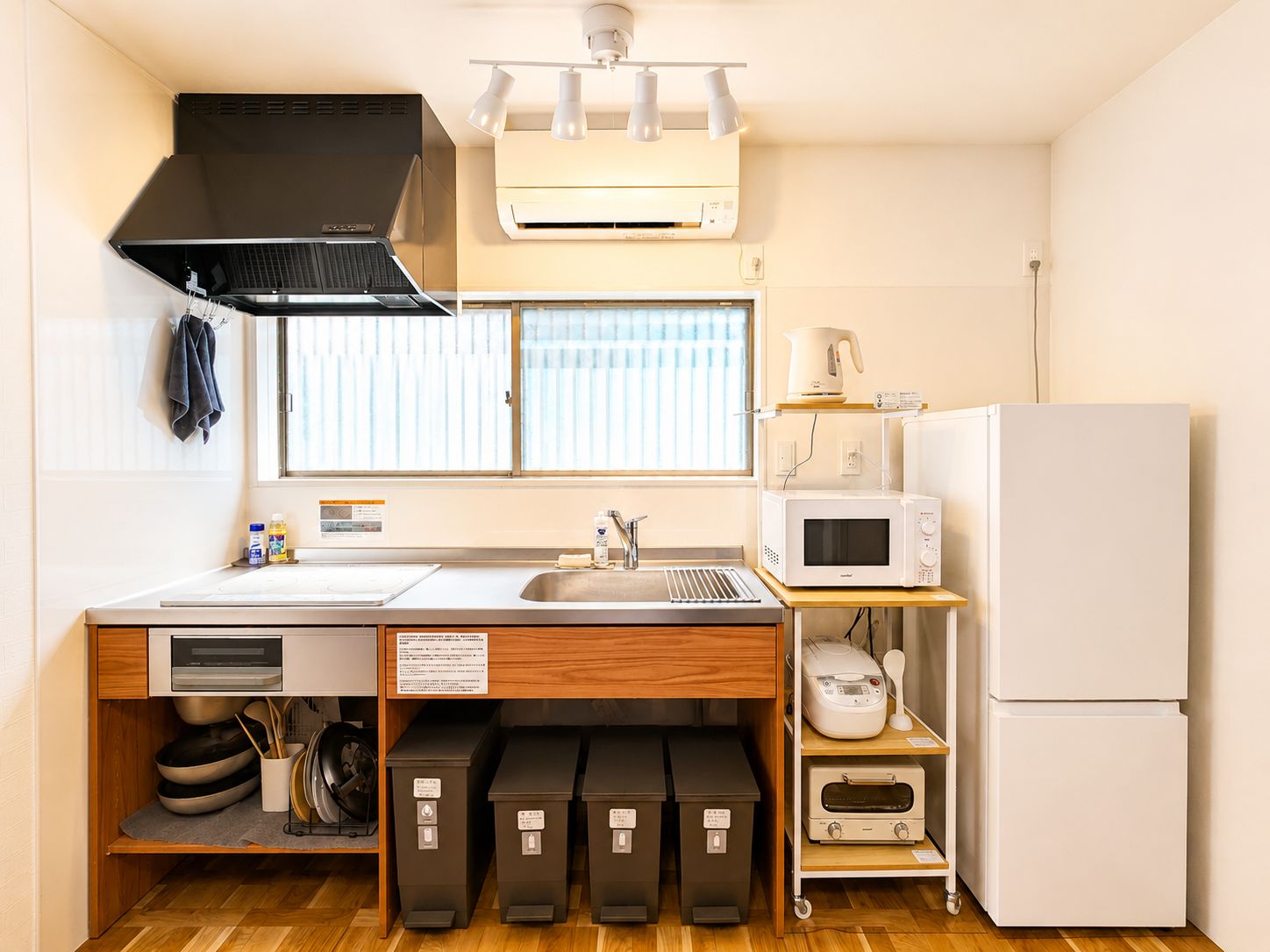 A compact kitchen with a microwave, a refrigerator, and a window with blinds.
