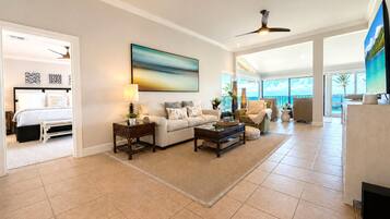 A spacious living area with a large window, a ceiling fan, and a view of the outdoors.