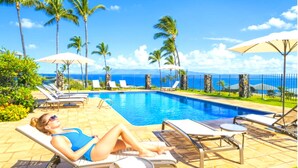 A poolside area with lounge chairs, umbrellas, and a view of the ocean. - Kapalua Bay Villas | 2-Bedroom Ocean View Villa | Car Incl. w/ 6+ Nights | KBV-16B3 by KBM (Lahaina)
