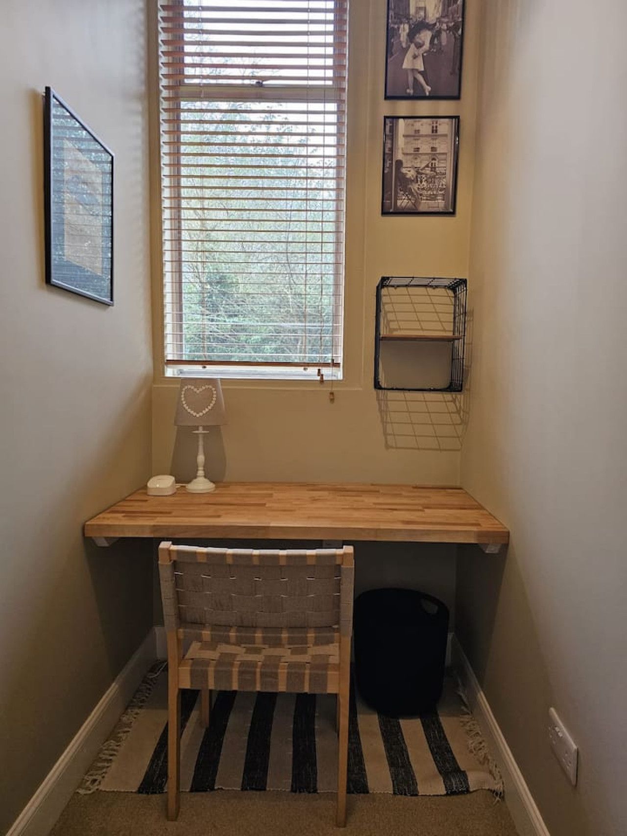 A corner room with a desk, chair, window, and wall-mounted storage.