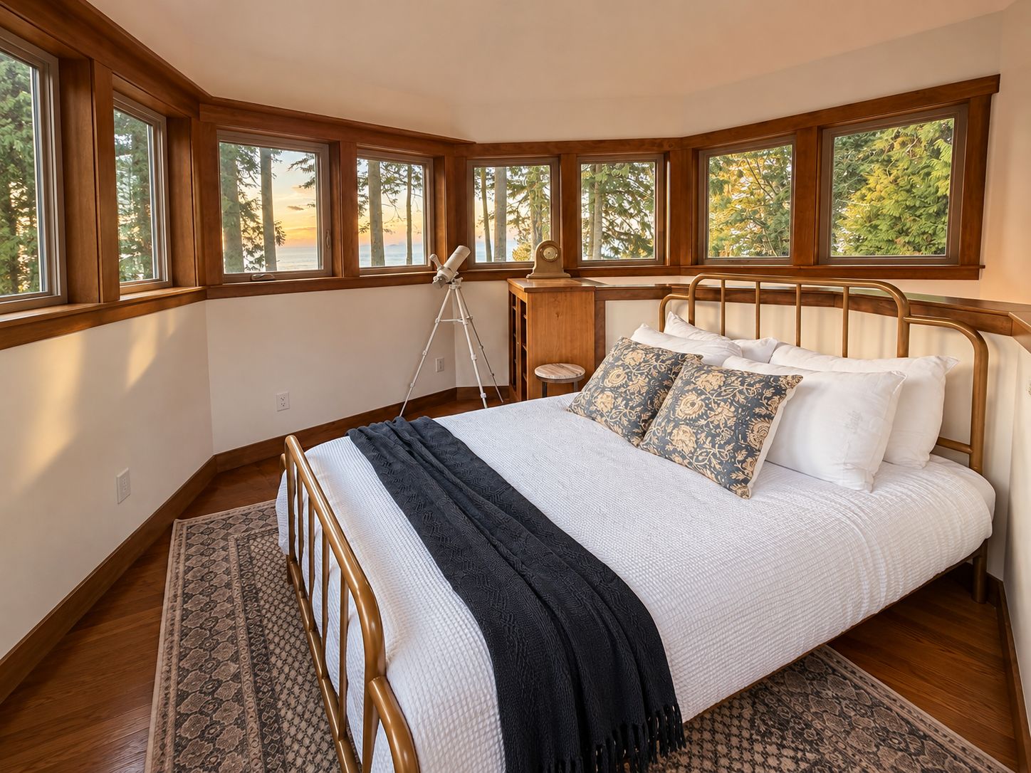 Quarto com cama, telescópio e grandes janelas com vista para árvores.