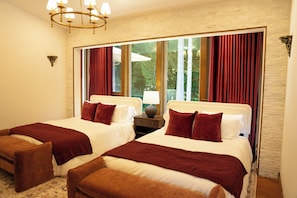 Ein Hotelzimmer mit zwei Betten, einer Kandelaber, einem Nachttisch und einem Fenster mit Vorhängen.