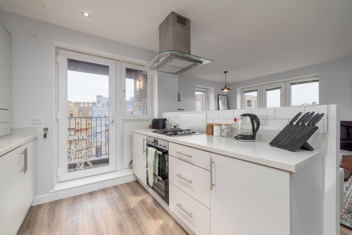 A modern kitchen with a gas stove, oven, and a glass range hood.
