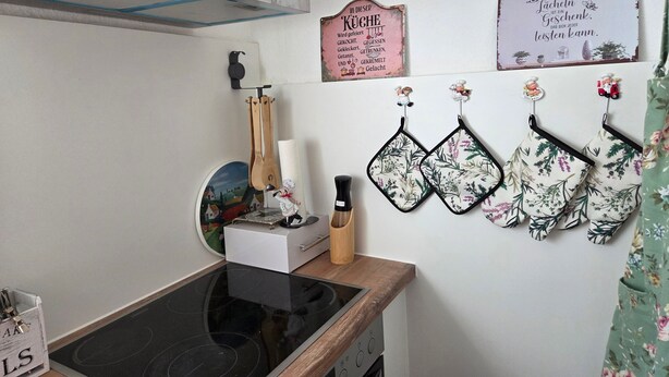 Een keuken met een fornuis, een inbouwoven en een klok.