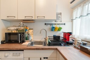 Une cuisine équipée d’un four à micro-ondes, d’un évier et de divers ustensiles de cuisine.
