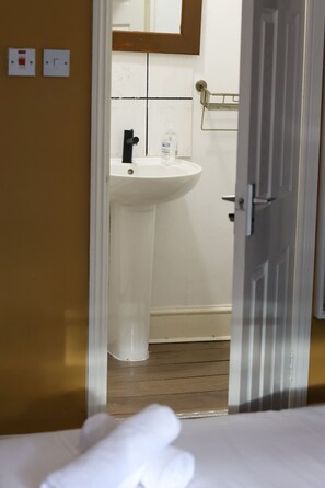 Een hotelkamer met een bed, een wit wastafelmeubel en een spiegel erboven.