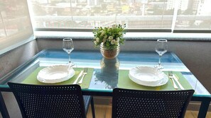 Una mesa de comedor con dos sillas, un florero con flores y dos copas de vino.