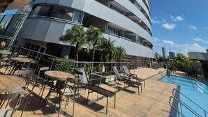 A modern hotel with a curved facade, outdoor pool, and lounge area with chairs and tables. - Vrbo Property (Sacramenta)