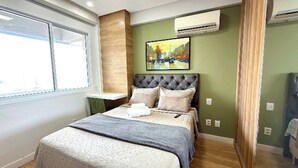 A bedroom with a bed, a window, an air conditioner, and a painting on the wall. - Vrbo Property (Sacramenta)