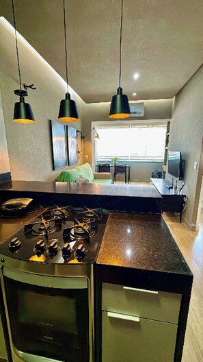Una cocina moderna con estufa a gas, iluminación colgante y vista al comedor.