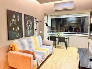 Ein modernes Wohnzimmer mit einer Couch, einem Esstisch mit Stühlen und Bildern an den Wänden.