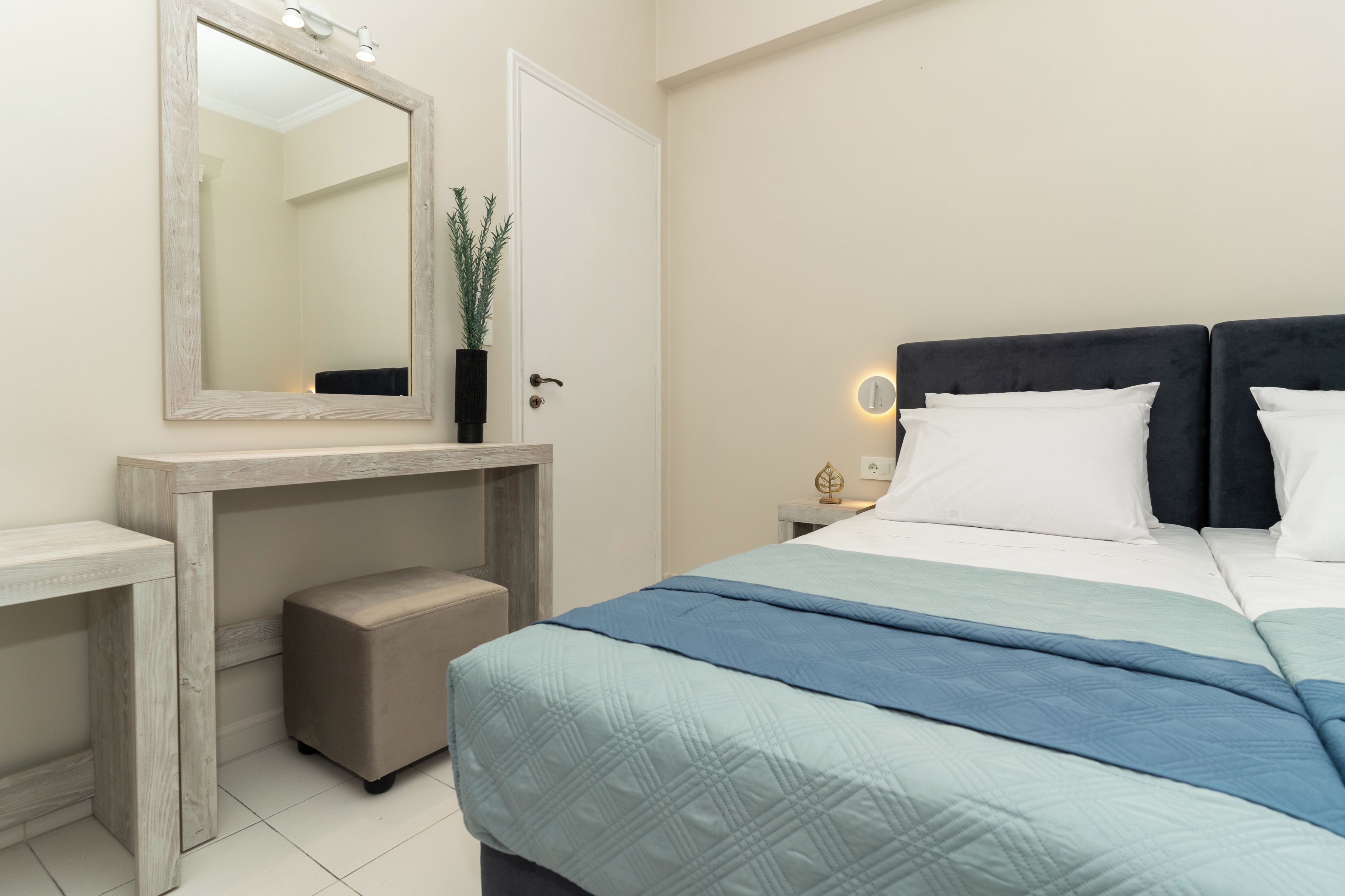 A bedroom with a bed, bedside table, nightstand, and a mirror.
