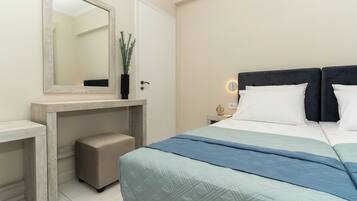 A bedroom with a bed, bedside table, nightstand, and a mirror.