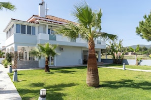 Ein zweistöckiges Haus mit einem Ziegeldach, einem gepflegten Rasen und einer Palme im Vordergrund.