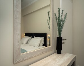 Ein Schlafzimmer mit einem Bett, einem Nachttisch, einem Spiegel und einer Zimmerpflanze.