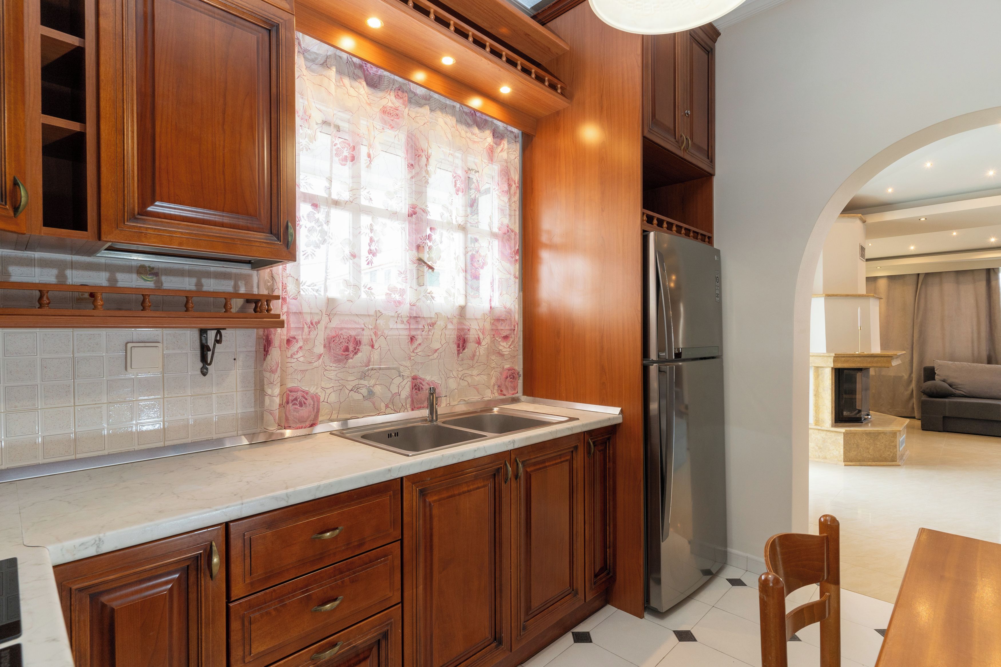 A kitchen with wooden cabinets, a stainless steel refrigerator, and a tiled backsplash.