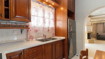 A kitchen with wooden cabinets, a stainless steel refrigerator, and a tiled backsplash.