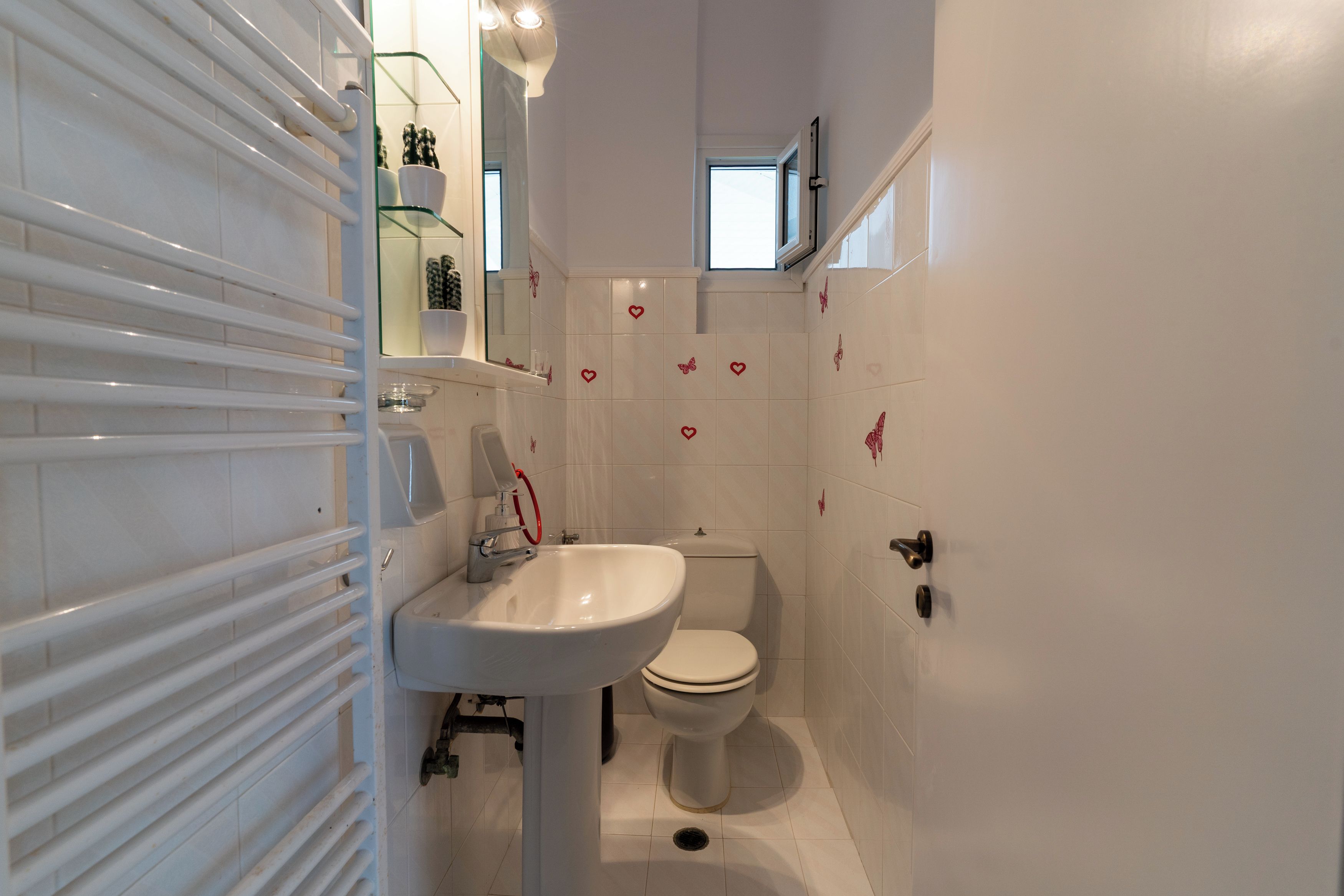 Een badkamer met een wit wastafel, toilet en glazen planken met toiletartikelen.