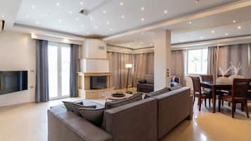 A modern living room with a sectional sofa, a flat-screen TV, a fireplace, and a dining area with a table and chairs.