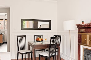 A dining area with a table set for four, a mirror above the table, and a fireplace with a lamp to the right. - Elegant Apartment Near Eiffel Tower (Paris)