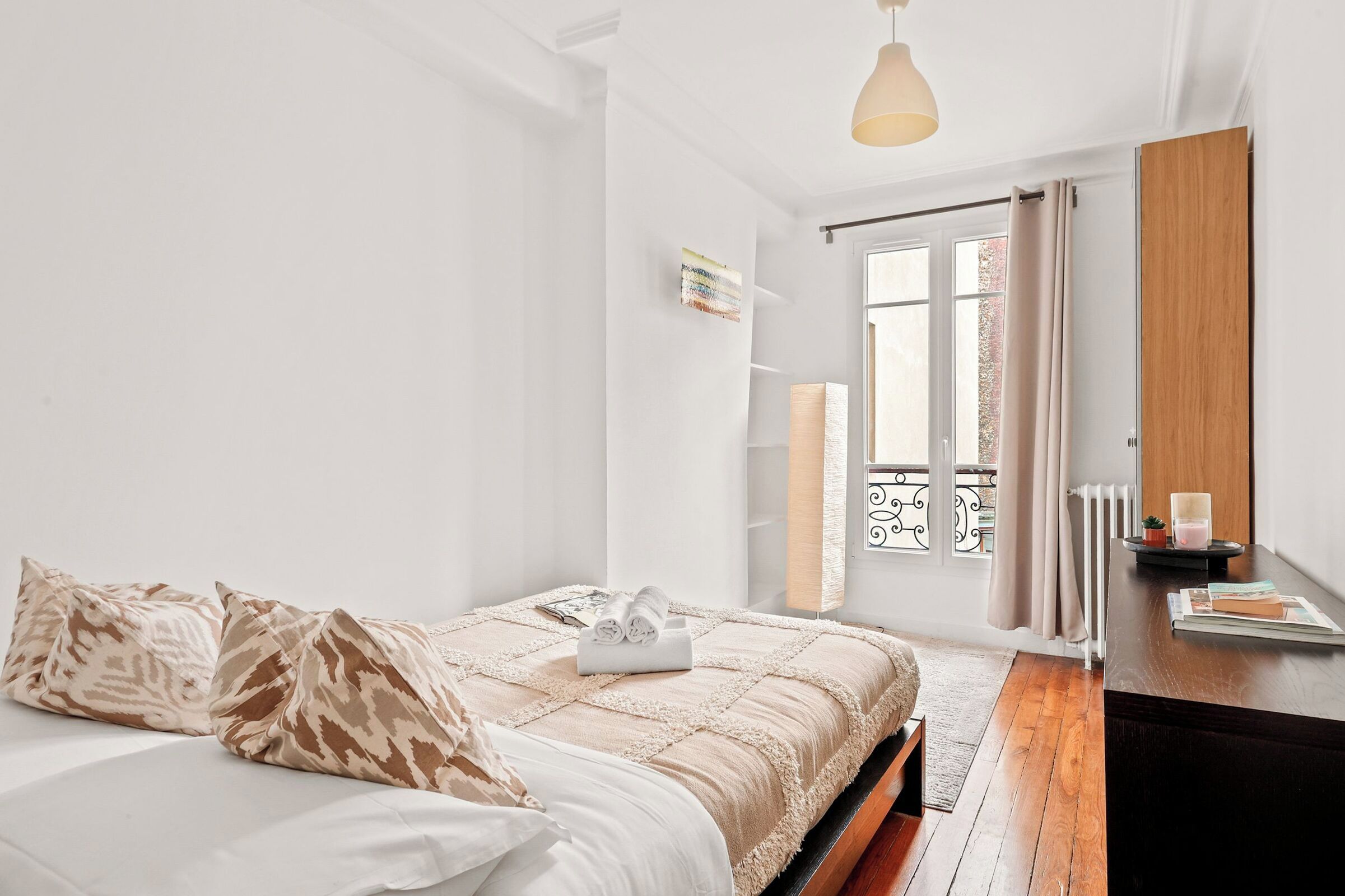 A bedroom with a bed, a bedside table, a lamp, and a window with curtains.