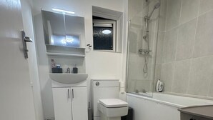 Un baño pequeño con inodoro, lavamanos y ducha.