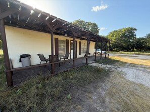 Un espace extérieur abrité, avec des tables et des chaises, une poubelle et un véhicule garé au fond.