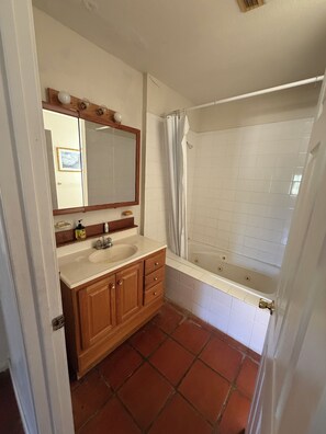 Casa de banho com lavatório, espelho, armário e banheira.