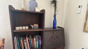 Ein Zimmer mit einem Holzbücherregal, einer blauen Vase mit Pflanze und einem an der Wand montierten Telefon.