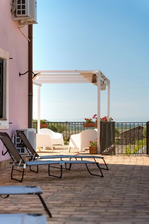 A terrace with a white pergola, two white lounge chairs, and a table. - Oasi Orange villa with Jacuzzi (Sicilia)