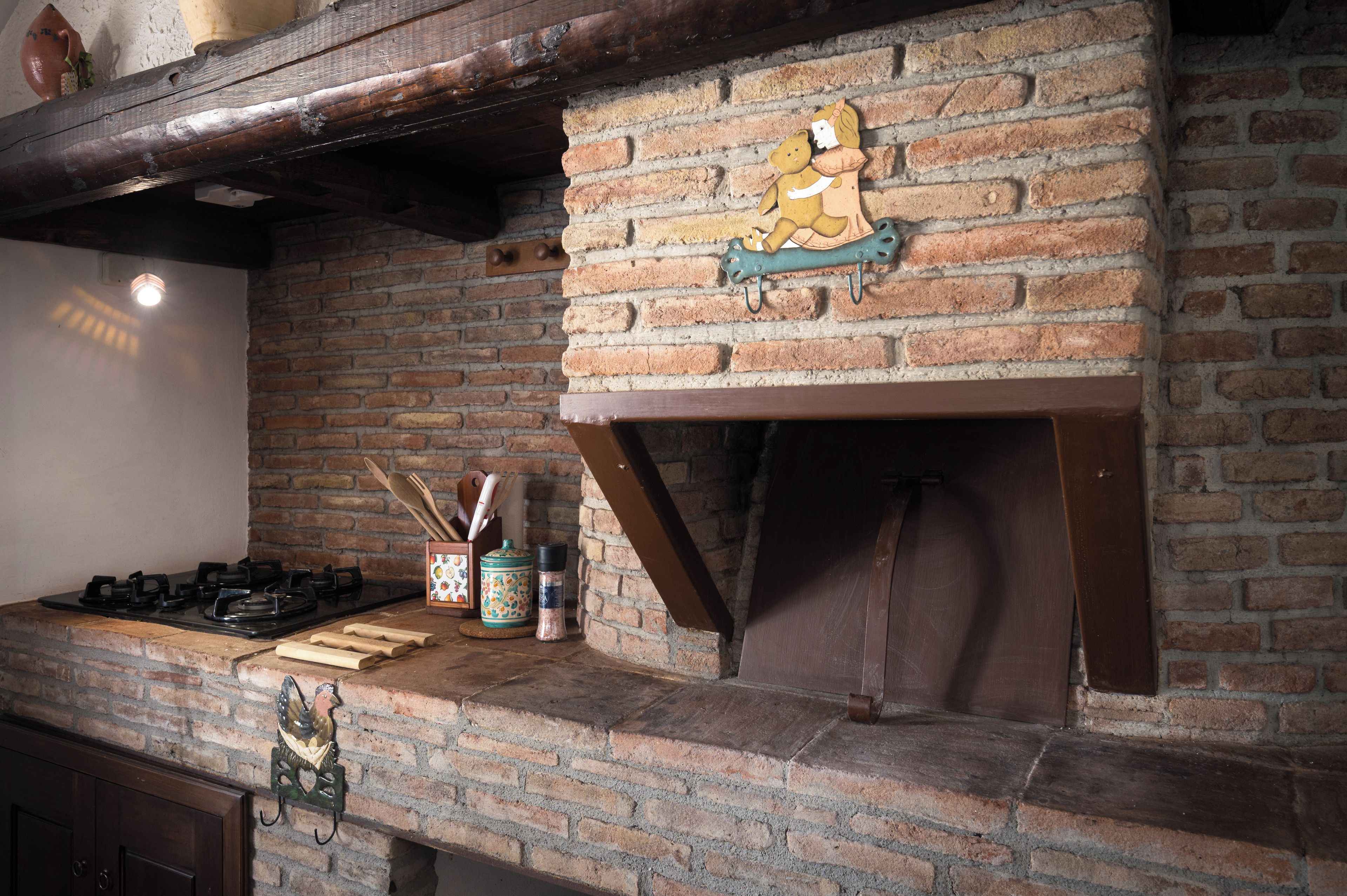 Une cuisine avec un mur en briques, une poutre en bois et une décoration suspendue.