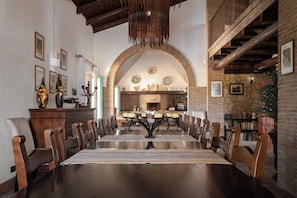 A dining area with a long table, chairs, and a brick fireplace. - Oasi Orange villa with Jacuzzi (Sicilia)