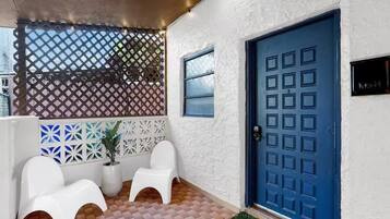 Una habitación con puerta azul, paredes blancas y suelo estampado.