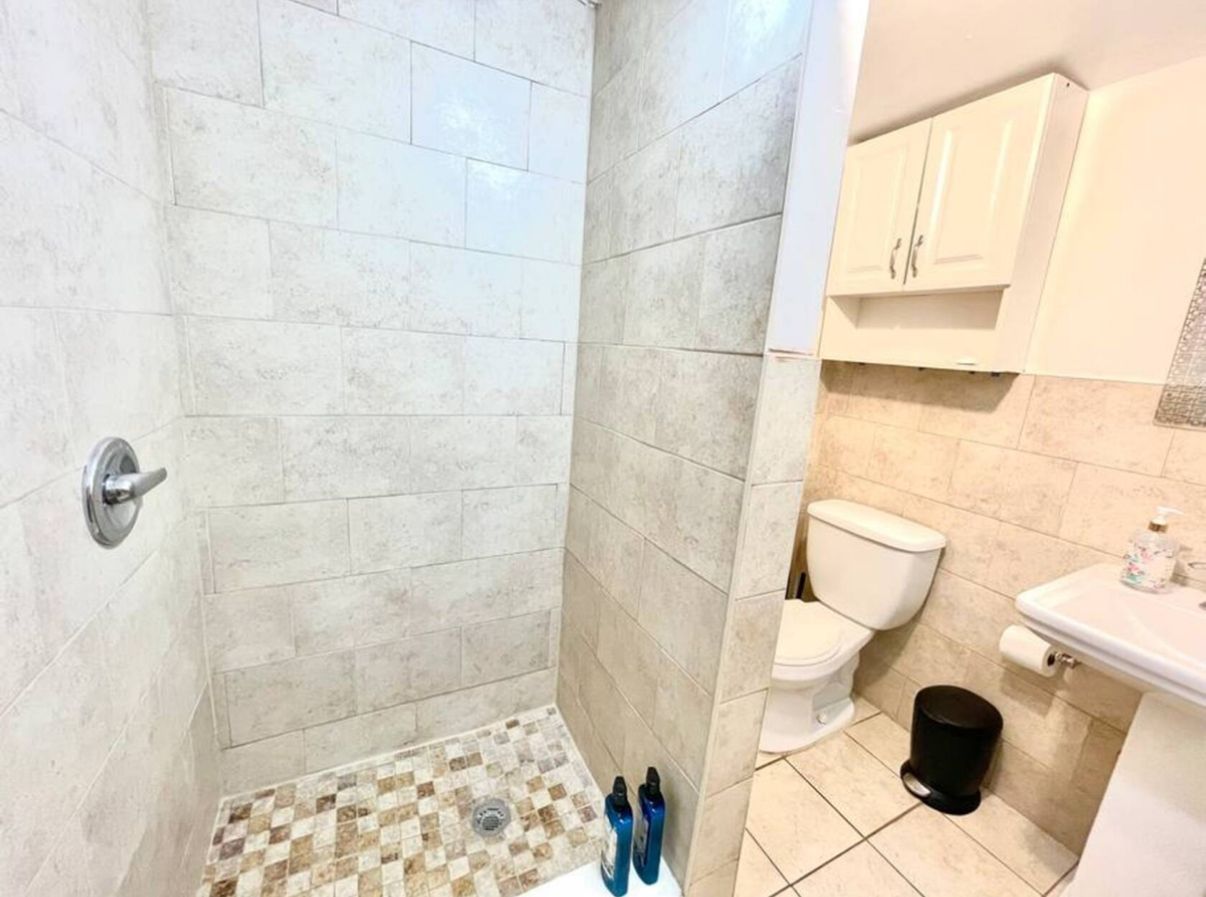 Een badkamer met douche, toilet, wastafel en betegelde vloer.