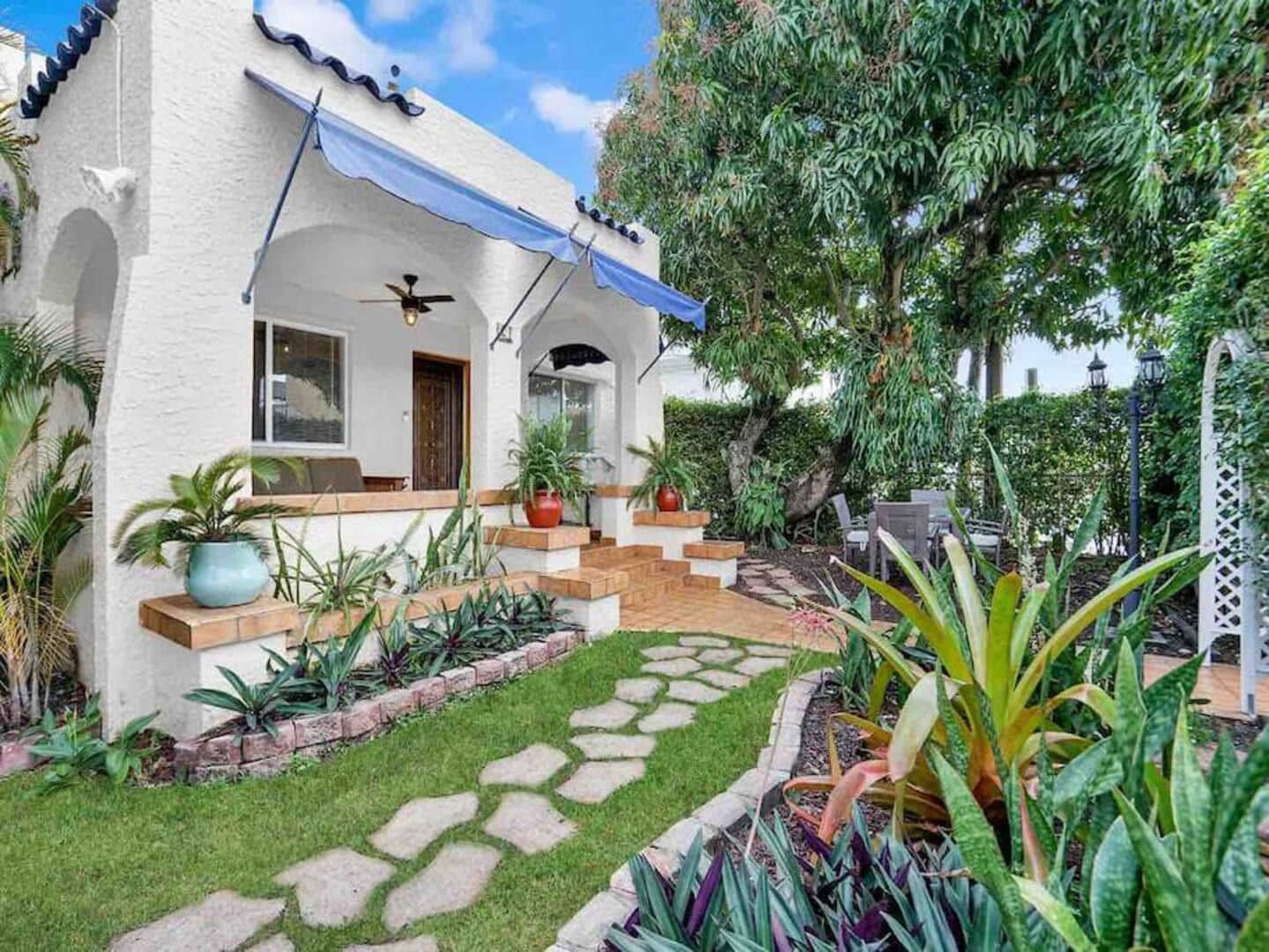 A house with a patio, a ceiling fan, and a variety of plants.