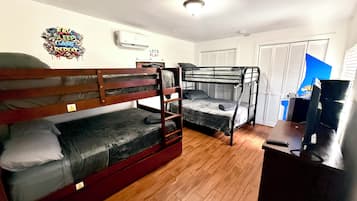 Un dormitorio con literas, un escritorio, una silla y un televisor.