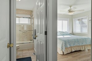 Un dormitorio con cama, ventilador de techo y ventana con persianas.