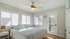 A bedroom with a bed, a nightstand, a ceiling fan, and a door with a window. - Pet-Friendly, 5 min walk to beach & ferry (Ocean Beach)